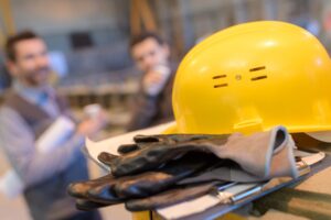 Two managers assess a hardhat and gloves to prevent occupational injuries