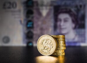 A stack of pound coins in front of a £20 note.