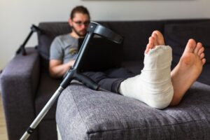 A man sitting in a sofa in a cast after injuries sustained in a workplace accident