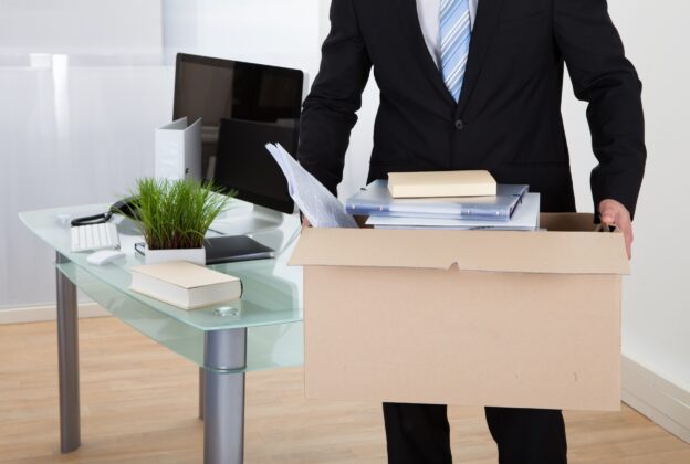 Someone carrying a box of their things out of an office after being fired.