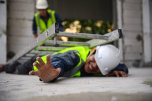 A construction worker lying on the ground with a ladder on top of them.