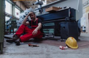 An injured worker sitting on the ground after a workplace accident.