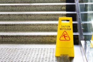 YELLOW WET FLOOR HEALTH AND SAFETY HAZARD SIGN NEAR FLIGHT OF STAIRS